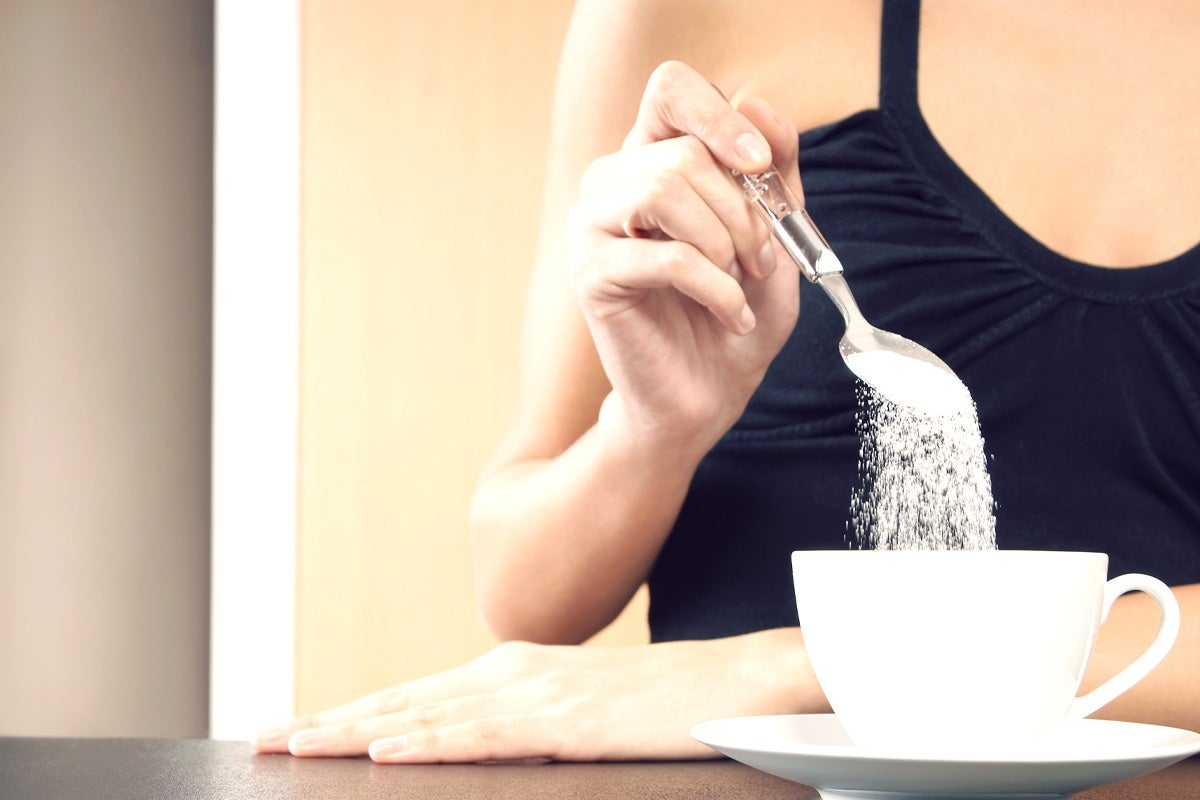 Pouring spoonful of sugar in coffee