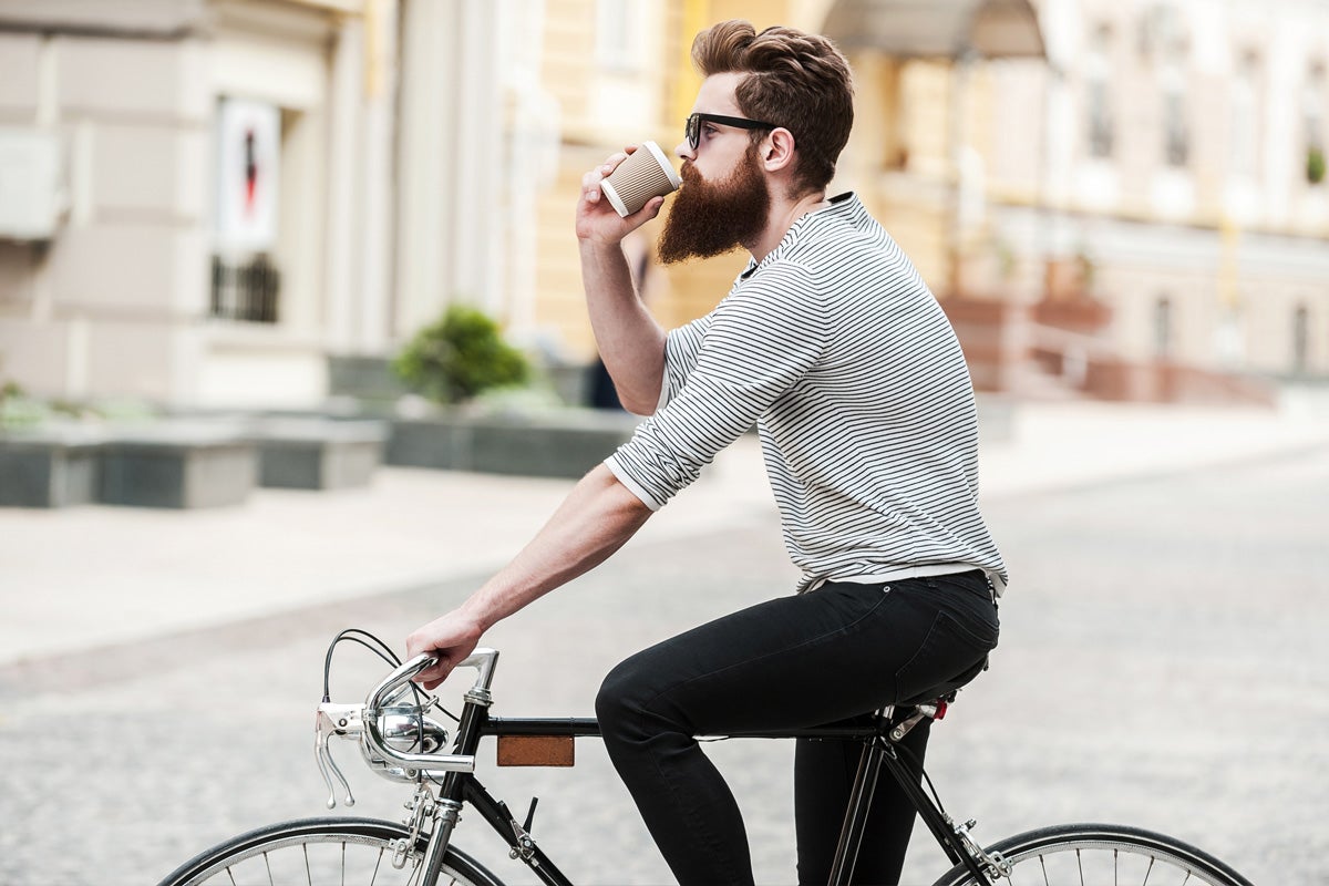 man drinking coffee and riding a bicycle